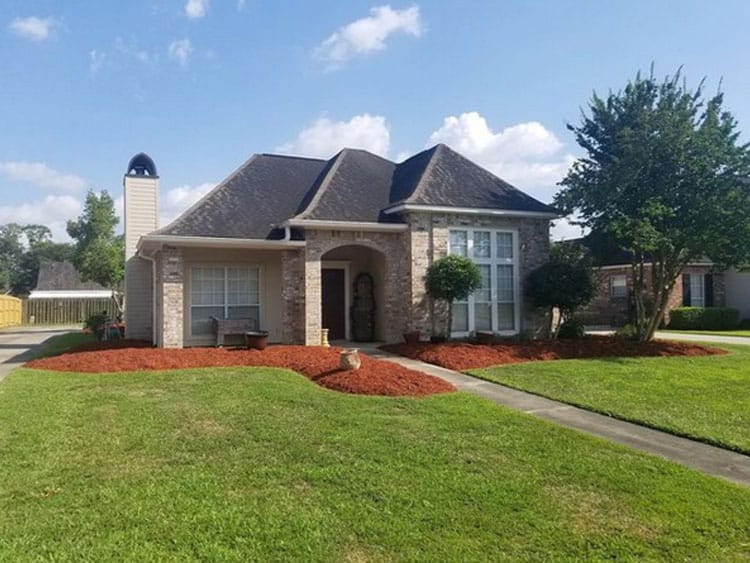 Brick house with manicured lawn and trees